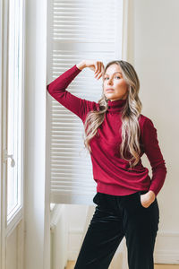 Fashion beauty portrait of happy young beautiful woman with blonde long curly hair in bordo sweater 