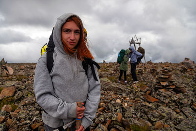 A portrait of a stylish red-haired female traveler with a backpack on a high mountain background