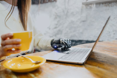 Midsection of woman using laptop on table