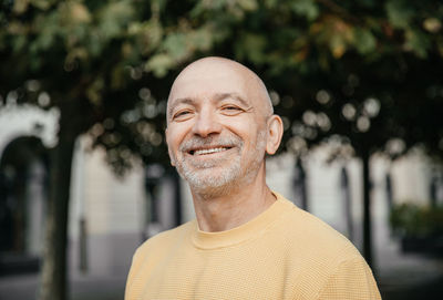 Elderly man in yellow sweater expressing joy and happiness in urban park