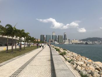 Footpath amidst buildings in city against sky