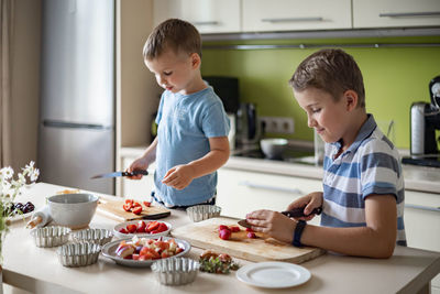 Boys slicing fruits in kitchen