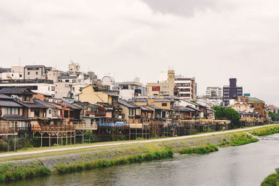 Buildings by river against sky in city