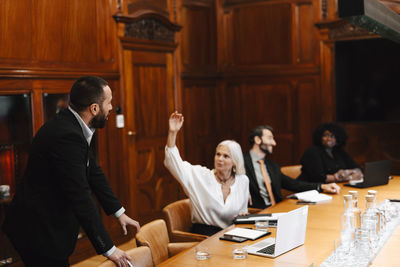 Businesswoman discussing with businessman during meeting in board room