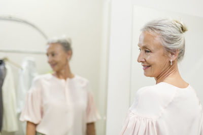 Smiling senior woman in a boutique reflected in mirror