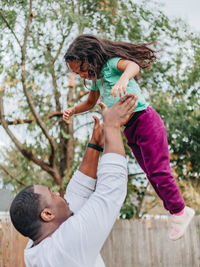 Black or african american father in white shirt in the back yard playing with mixed race daughter