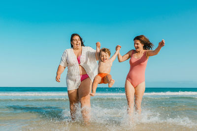 Full length of young woman with arms raised standing at beach