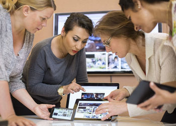 Female photo editors discussing over digital tablet in creative office