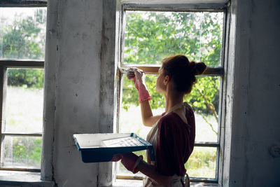 Side view of woman painting window
