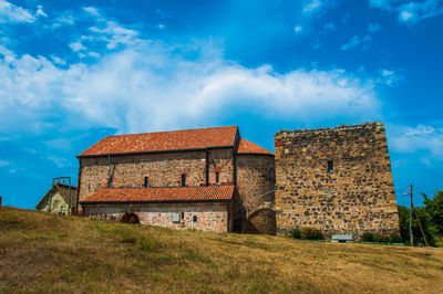 Low angle view of old house on field against sky