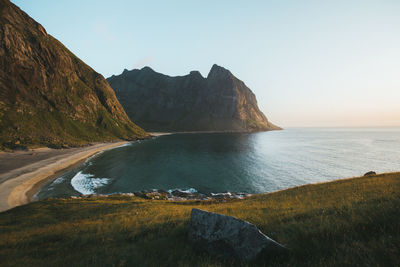 Scenic view of sea by mountains against clear sky