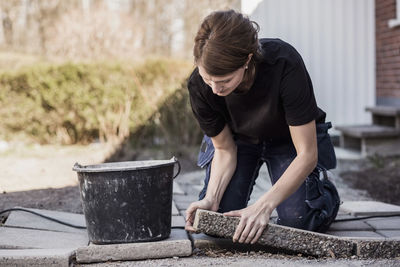 Female carpenter positioning stone tile in yard