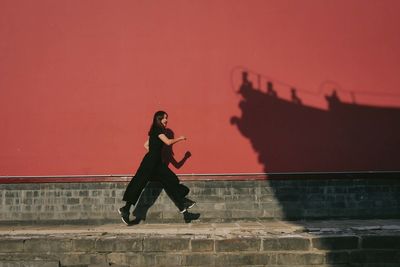 Woman with red umbrella against sky during sunset