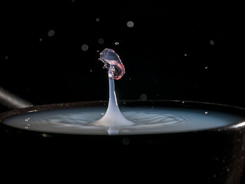 Close-up of water drop on glass against black background