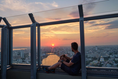 Man looking at cityscape against sky during sunset. yekaterinburg, visotskiy skyscraper.