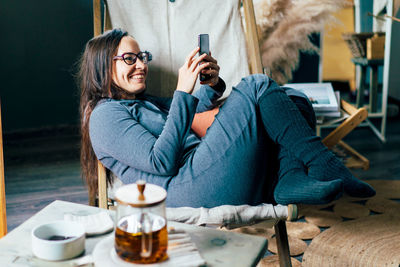 Young woman using phone while sitting on table