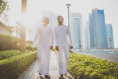 Men walking on footpath against building