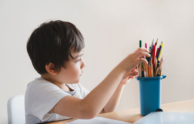 Rear view of boy sitting against wall