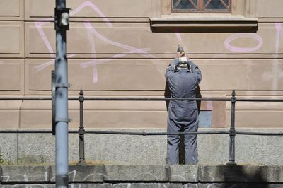 Rear view of man working on wall 