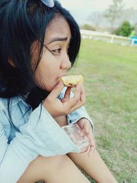 Young woman eating food on field