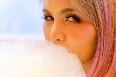 Close-up portrait of young woman eating cotton candy