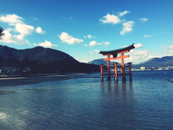 Itsukushima shrine in river against mountains and blue sky