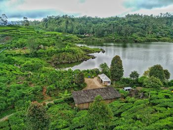 High angle view of trees and house by lake against sky