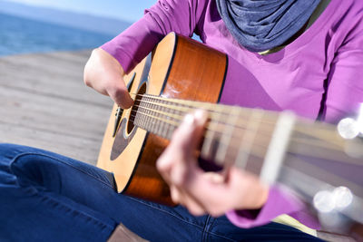 Midsection of man playing guitar