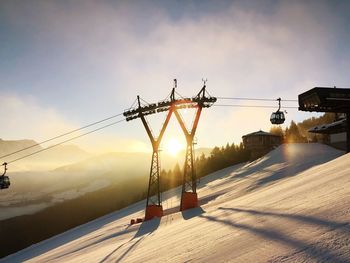 Ski lift over snow covered mountain against sky