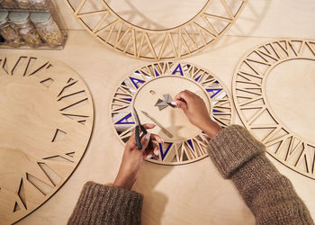 High angle view of man holding clock against wall