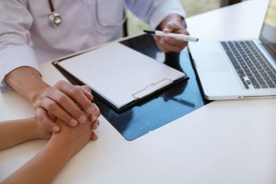 Midsection of doctor consoling patient in hospital