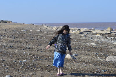 Full length of girl standing at beach against clear sky