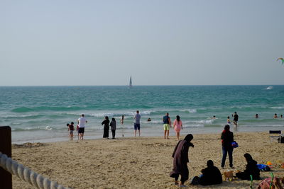 People on beach against clear sky