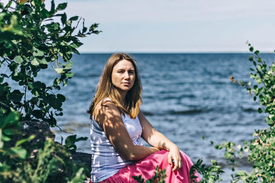 A pregnant woman is sitting on the beach