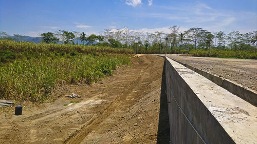 Road amidst field against sky