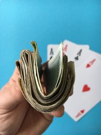 Cropped image of hand holding paper currency with aces cards at casino table