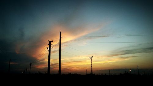 Low angle view of silhouette electricity pylon against sky during sunset