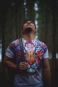 Midsection of young woman with eyes closed standing against trees