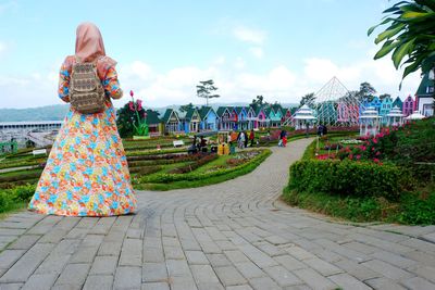 Rear view of woman standing on footpath against sky