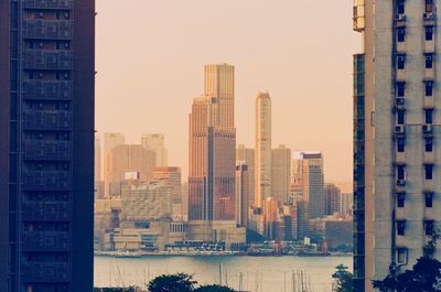 Buildings and river in city against clear sky