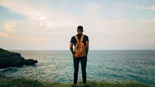 Rear view of man looking at sea against sky