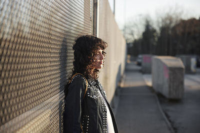 Young woman leaning on fence and looking away