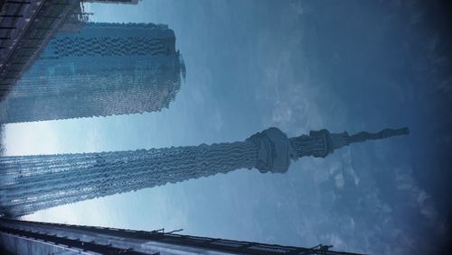 Low angle view of skyscrapers against cloudy sky