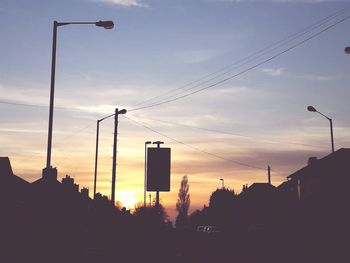 Silhouette street against sky at sunset