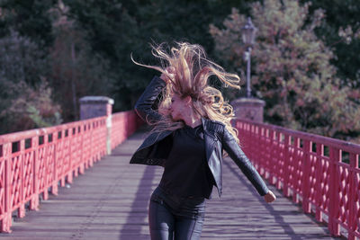 Young woman with blond hair standing on footbridge