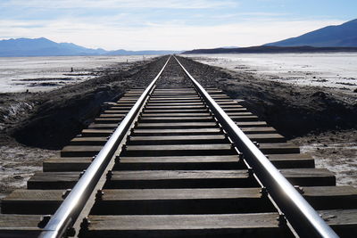 Close-up of railroad tracks amidst field against sky