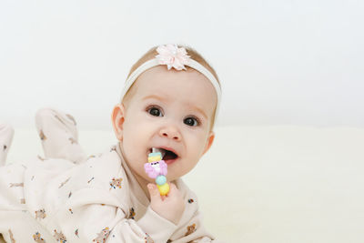 Close-up of cute girl eating lollipop against white background