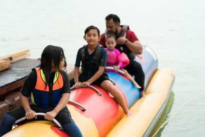 Rear view of people sitting on boat