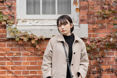 Young woman standing against wall