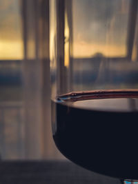 Close-up of wine in glass on table at sunset